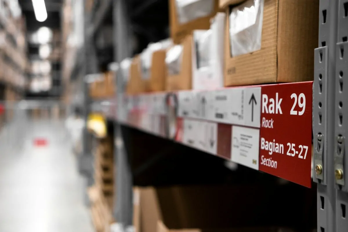 Warehouse storage rack labeled 'Rak 29' with stacked cardboard boxes, representing an organized inventory management system in a logistics and supply chain facility.