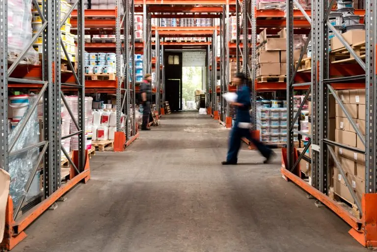 Workers moving through warehouse aisles filled with inventory as part of 3PL logistics and ecommerce fulfillment operations.